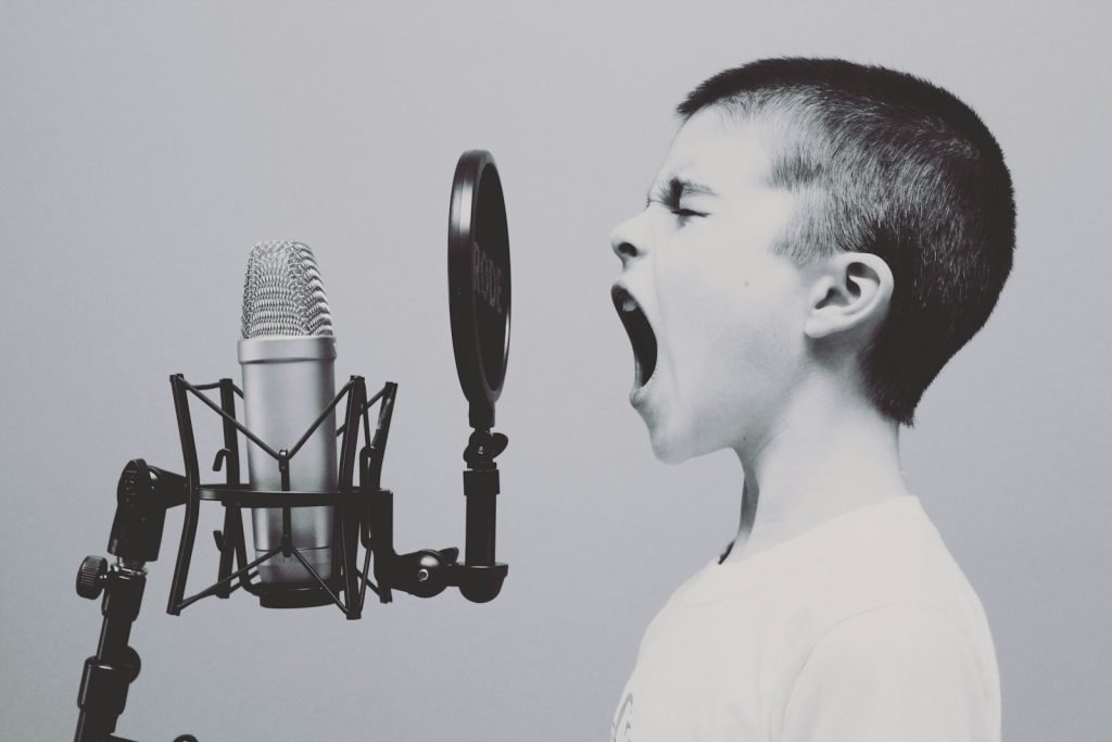 boy singing on microphone with pop filter, showing one way to communicate