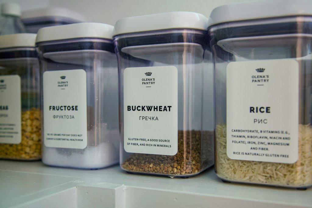 Labeled clear glass jars on white shelf, organized and aligned