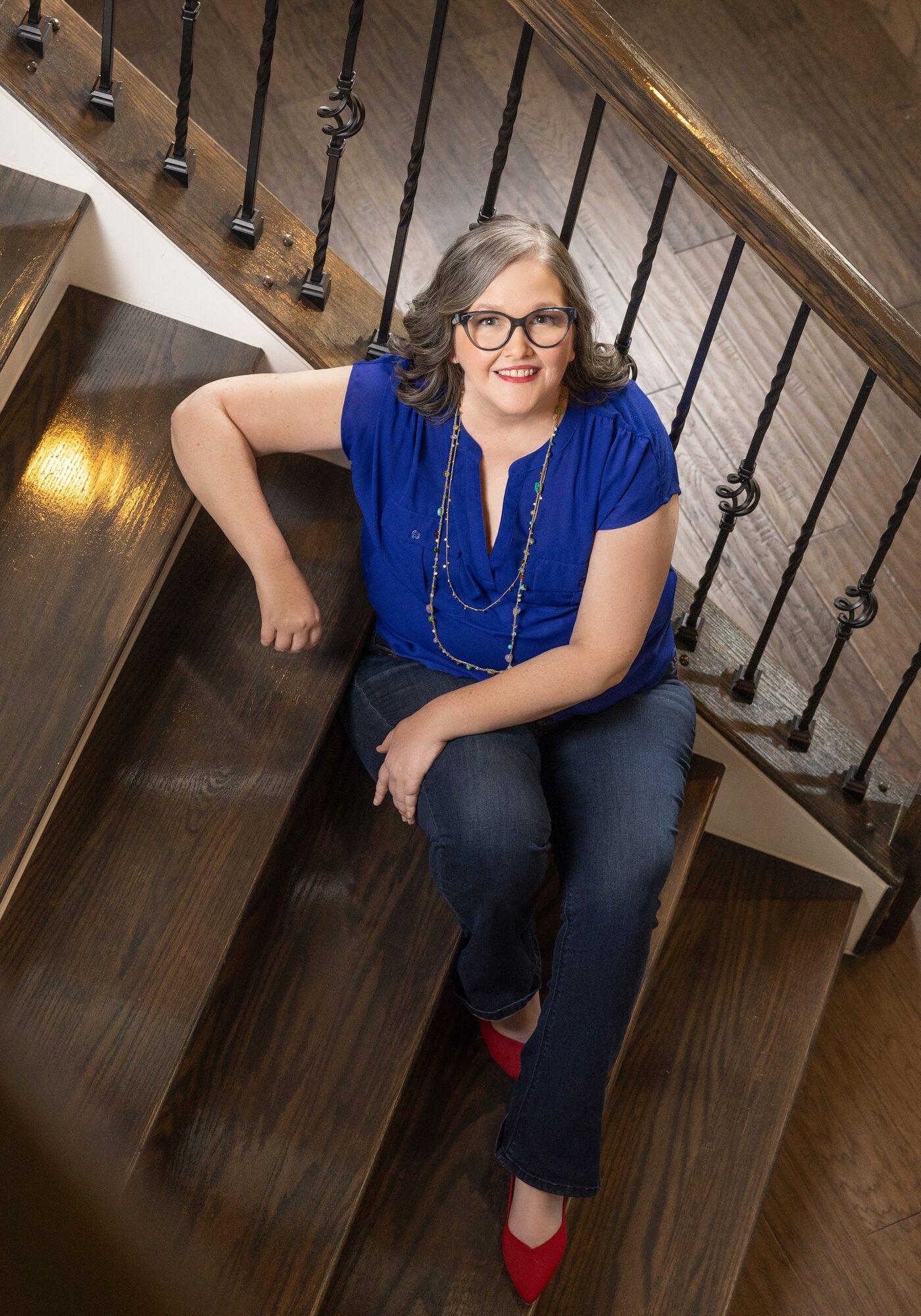 rachel-redshoes-stairs-squarevertical-2024-edit-web-res-2000px-2 Rachel Gaddis in blue shirt and jeans on stairs
